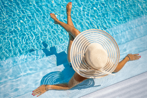 alt="Woman in a floppy sun hat lounging in a pool links to South Florida 55 and over listings."